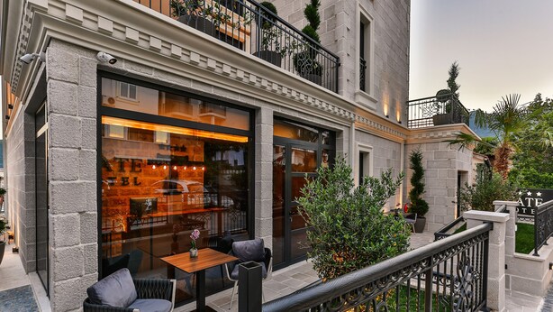 A hotel with a stone facade, outdoor seating, and a balcony with plants. - Hotel Tate by Aycon (Budva)