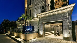 A hotel entrance with a sign, a motorcycle parked inside, and a cobblestone pathway. - Hotel Tate by Aycon (Budva)