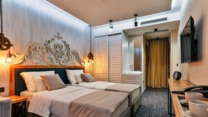 A hotel room with two beds, a wooden headboard, a desk with a telephone, and a television on the wall. - Hotel Tate by Aycon (Budva)