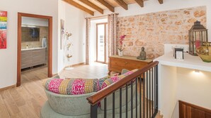 A modern interior with a wooden ceiling, a staircase with a cushioned seat, a stone wall, and a small Buddha statue. - Beautiful private villa for 6 guests with WIFI, private pool, TV and terrace (Santanyí)