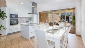 A modern kitchen with white cabinetry, a built-in oven, and a large island with seating. - Beautiful private villa for 6 guests with WIFI, private pool, TV and terrace (Santanyí)
