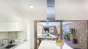 A modern kitchen with white cabinets, a marble countertop, and a view to an outdoor pool area. - Beautiful private villa for 6 guests with WIFI, private pool, TV and terrace (Santanyí)