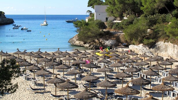 A beach with numerous thatched umbrellas and sun loungers, a rocky coastline, and boats in the water. - Beautiful private villa for 6 guests with WIFI, private pool, TV and terrace (Santanyí)