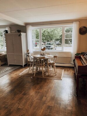 Enjoy a room with a large window offering a view of the outdoors, a dining table, and a piano.