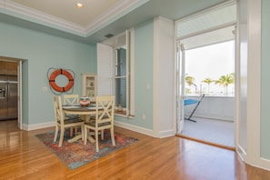 A dining area with a table and chairs, a life preserver decoration, and a view of a balcony with palm trees. - Gypsy's Palace at the Truman Annex in Key West (Key West)