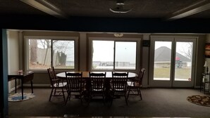 A dining room with a round table and chairs, large windows, and a view of the outdoors.