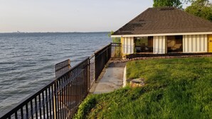 A house with a view of the water, a deck, and a grassy area.