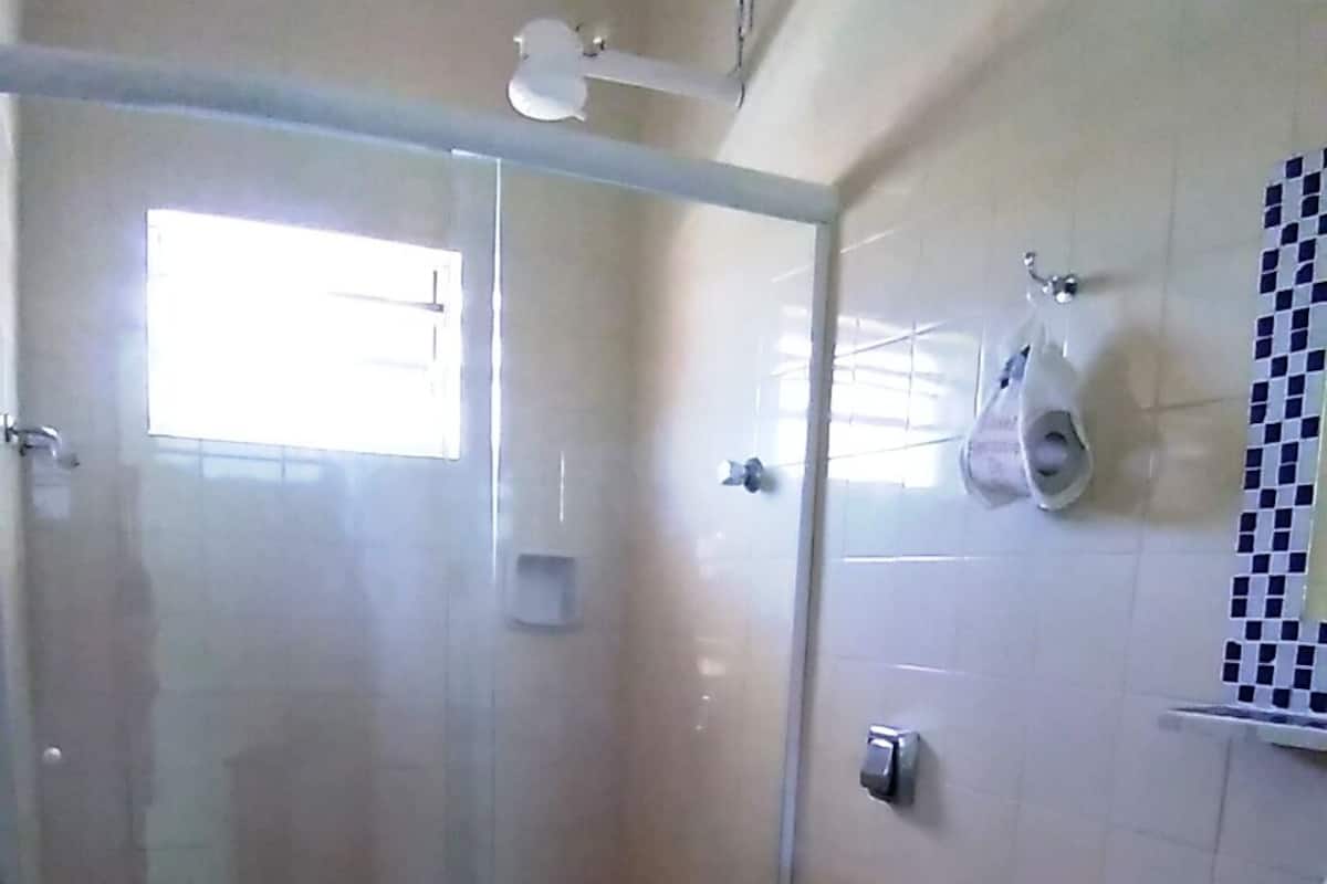 Un baño con inodoro, cabina de ducha, lavabo y pared de azulejos.