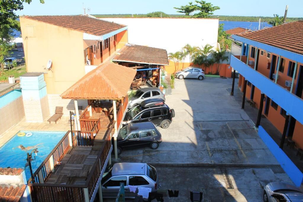 A residential area with a swimming pool, parked cars, and a building with a tiled roof.