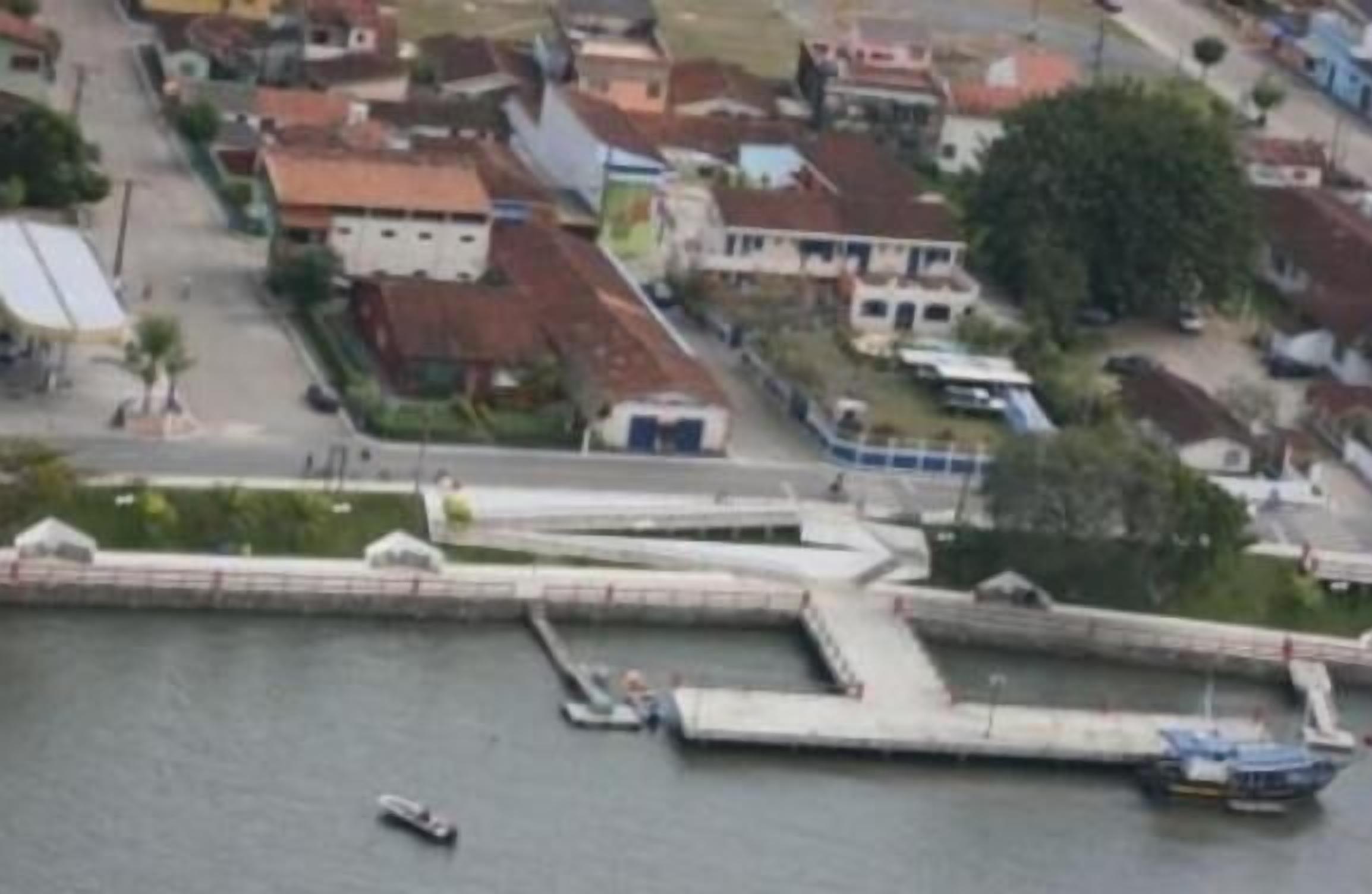 Luftaufnahme einer Küstenstadt mit einem Yachthafen, Häusern und einer Straße.