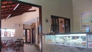 Ein Zimmer mit Holzbalkendecke, einem Aquarium, einer Couch und einem Essbereich mit Stühlen und einem Tisch.