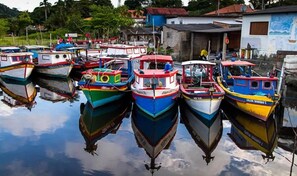 A marina with several boats docked in calm water, surrounded by buildings. - Hotel Recanto Do Sol (Cananeia)