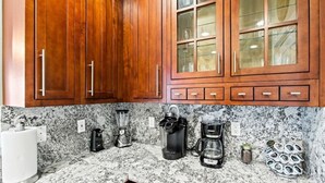 A kitchen with wooden cabinets, granite countertops, and various appliances including a coffee maker and a blender.