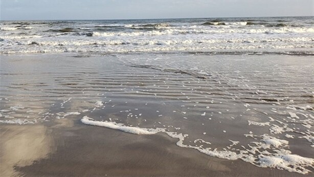 A beach with waves approaching the shore.