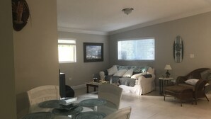 A living room with a glass dining table, two sofas, and a TV. - Stay in Paradise (Key Largo)