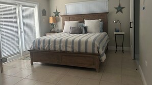 A bedroom with a wooden bed, a nightstand, a lamp, and a star decoration on the wall. - Stay in Paradise (Key Largo)