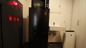 A compact kitchenette with a black refrigerator, a microwave, and a sink. - bnb+ Namba - Hostel (Osaka)