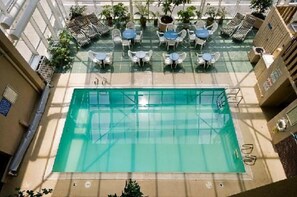 An indoor swimming pool with multiple lounge areas and seating around the perimeter. - Four Sails Resort - Oceanfront by the Neptune Statue (Virginia Beach)
