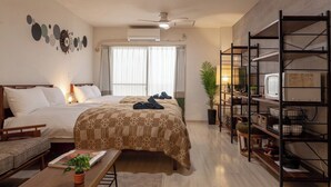 Una habitación de hotel con dos camas, un escritorio, una estantería y una ventana con cortinas.