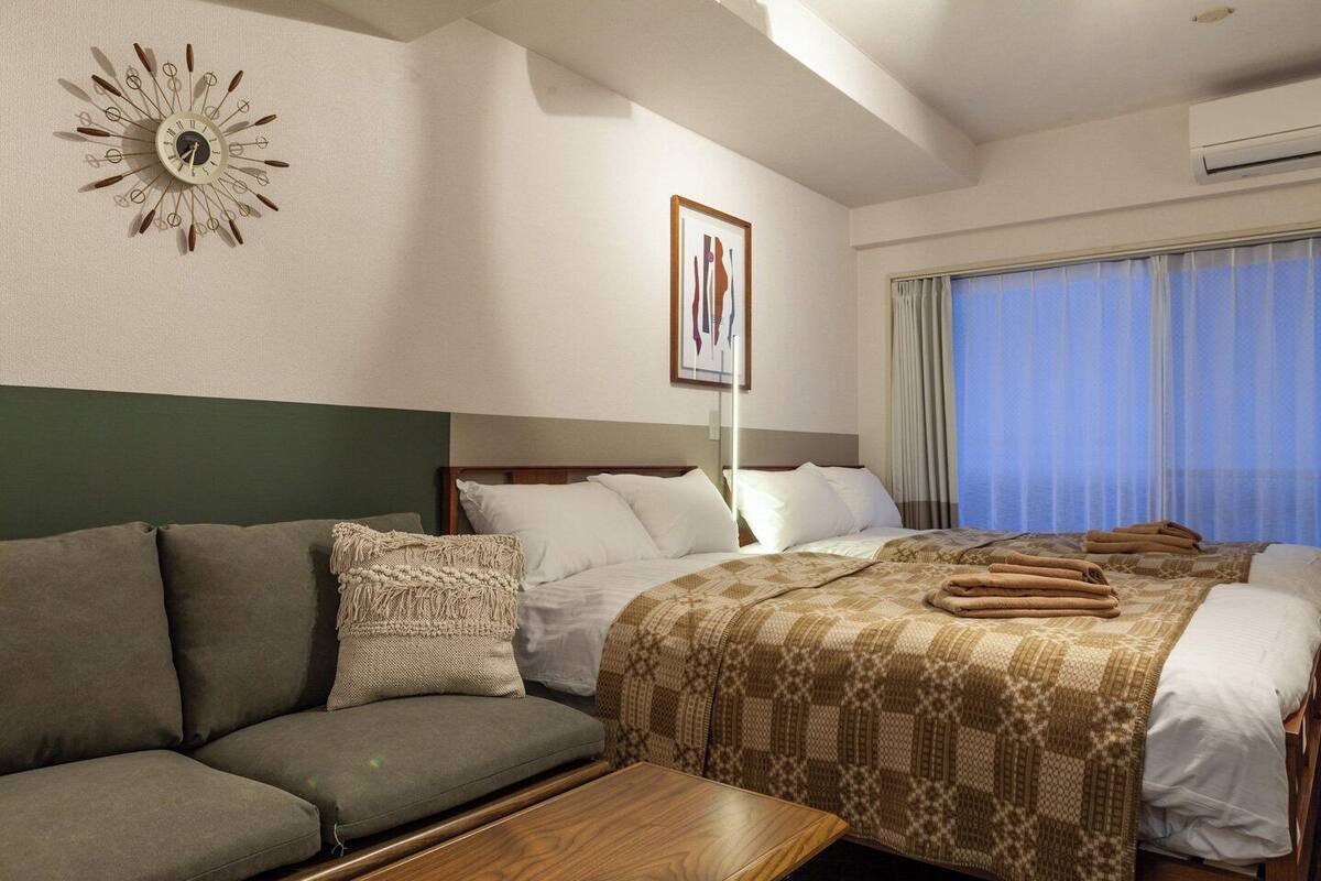 Una habitación de hotel con una cama, un sofá, una mesita de madera y un reloj de pared.
