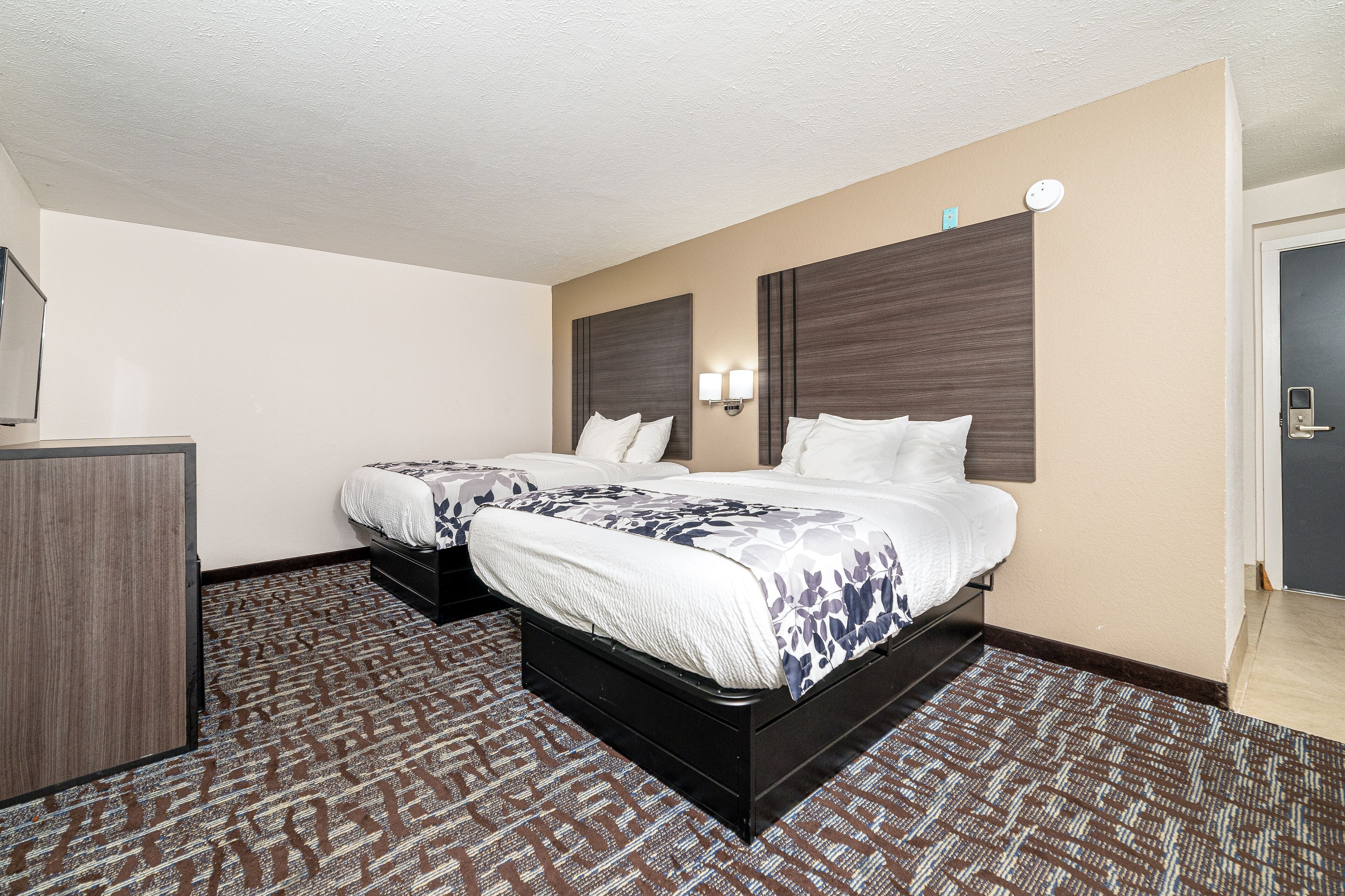 A hotel room with two beds, a desk, and a wardrobe.
