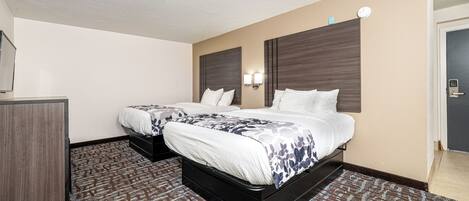 A hotel room with two beds, a desk, and a wardrobe.