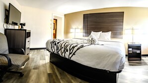 Une chambre d’hôtel avec un lit, un bureau, une chaise, une télévision et une lampe.