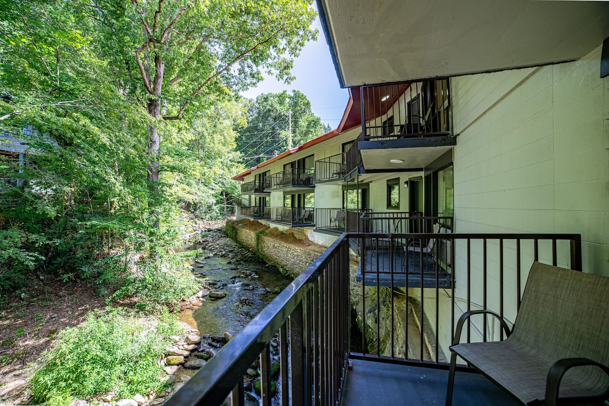 Un hôtel doté d’un balcon donnant sur un ruisseau, entouré d’une végétation luxuriante.