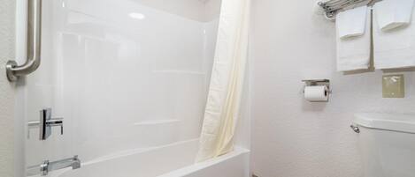 Un baño con bañera, cortina de ducha, inodoro y toallero con toallas.