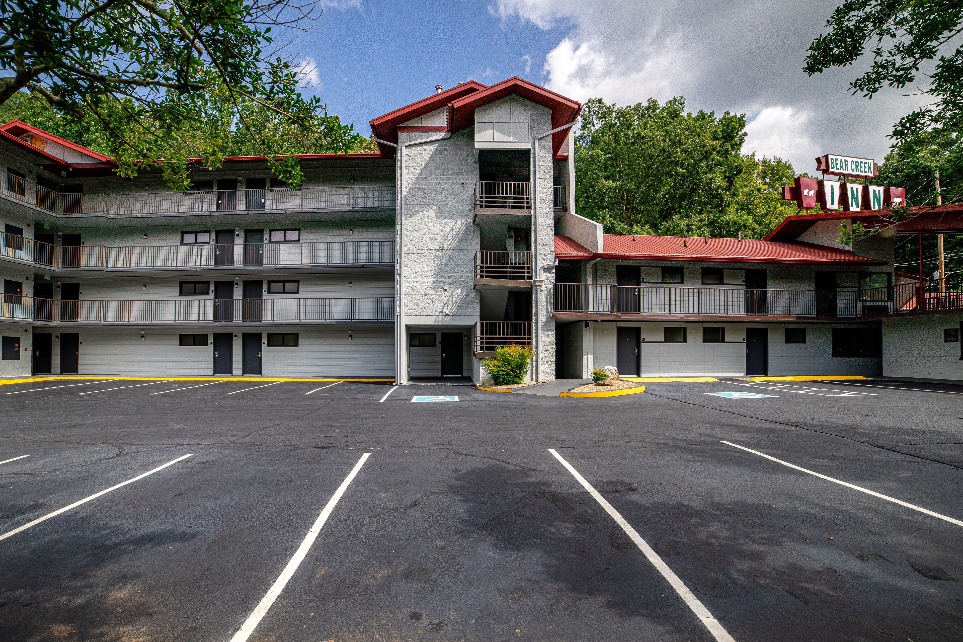 Un motel de varios pisos con una torre central, un estacionamiento y un cartel que indica que es el Bear Creek Inn.