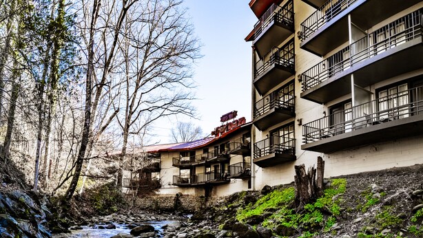 Un immeuble à plusieurs étages doté de balcons donnant sur un ruisseau aux rives rocheuses.