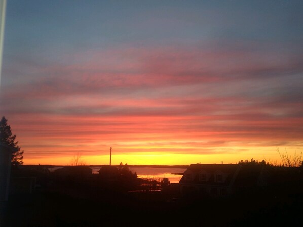 A sunset over a residential area with houses and a body of water.