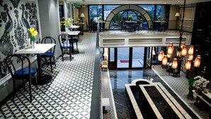 Un restaurant avec un sol à motifs noir et blanc, un balcon offrant une vue panoramique et un lustre.