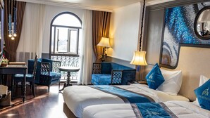 Une chambre d’hôtel avec deux lits, un bureau et un balcon.