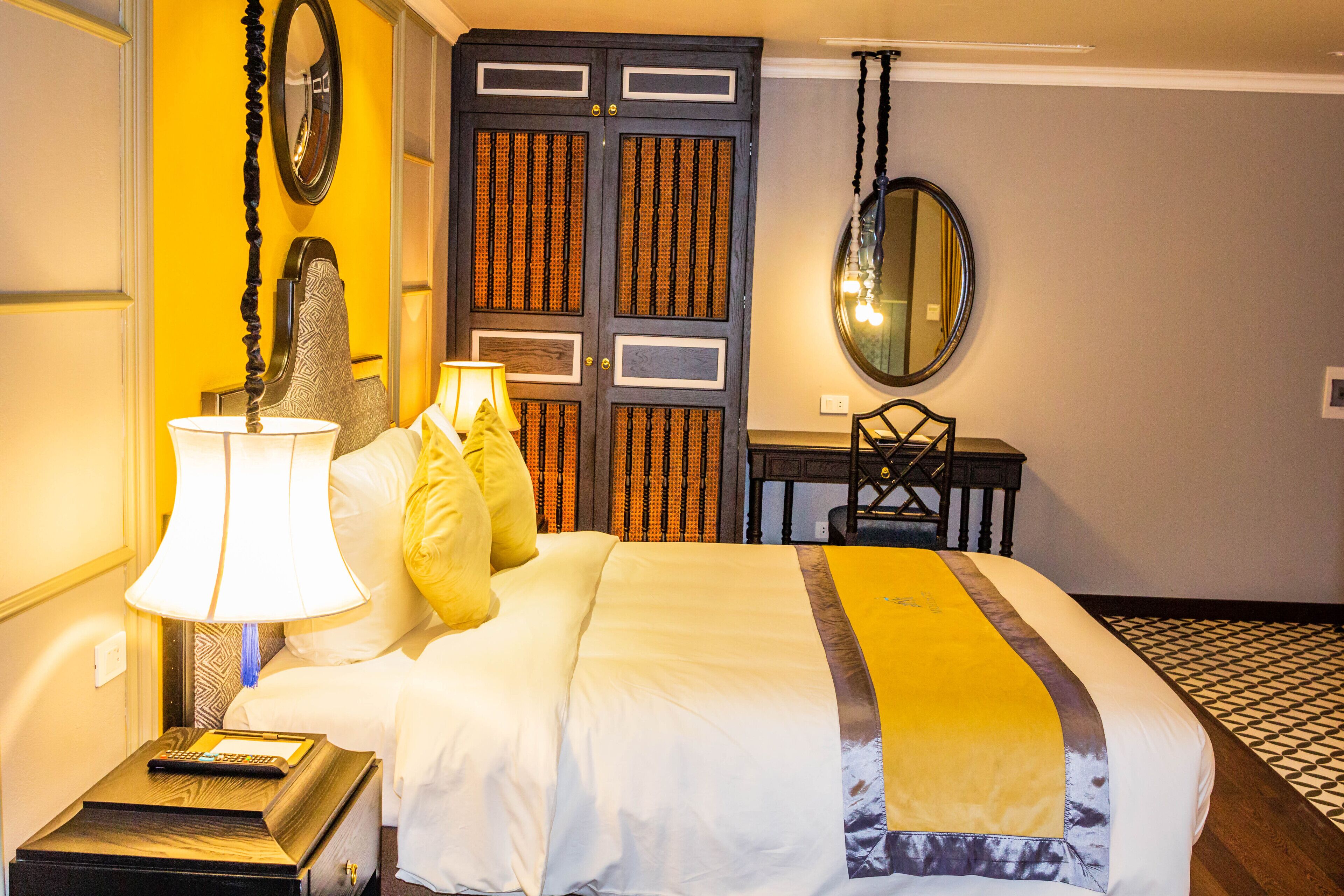 A hotel room with a bed, bedside lamps, a desk, and a chair.