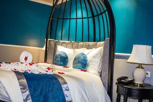 Una cama con dosel, una mesita de noche con lámpara y una pared de color aguamarina.