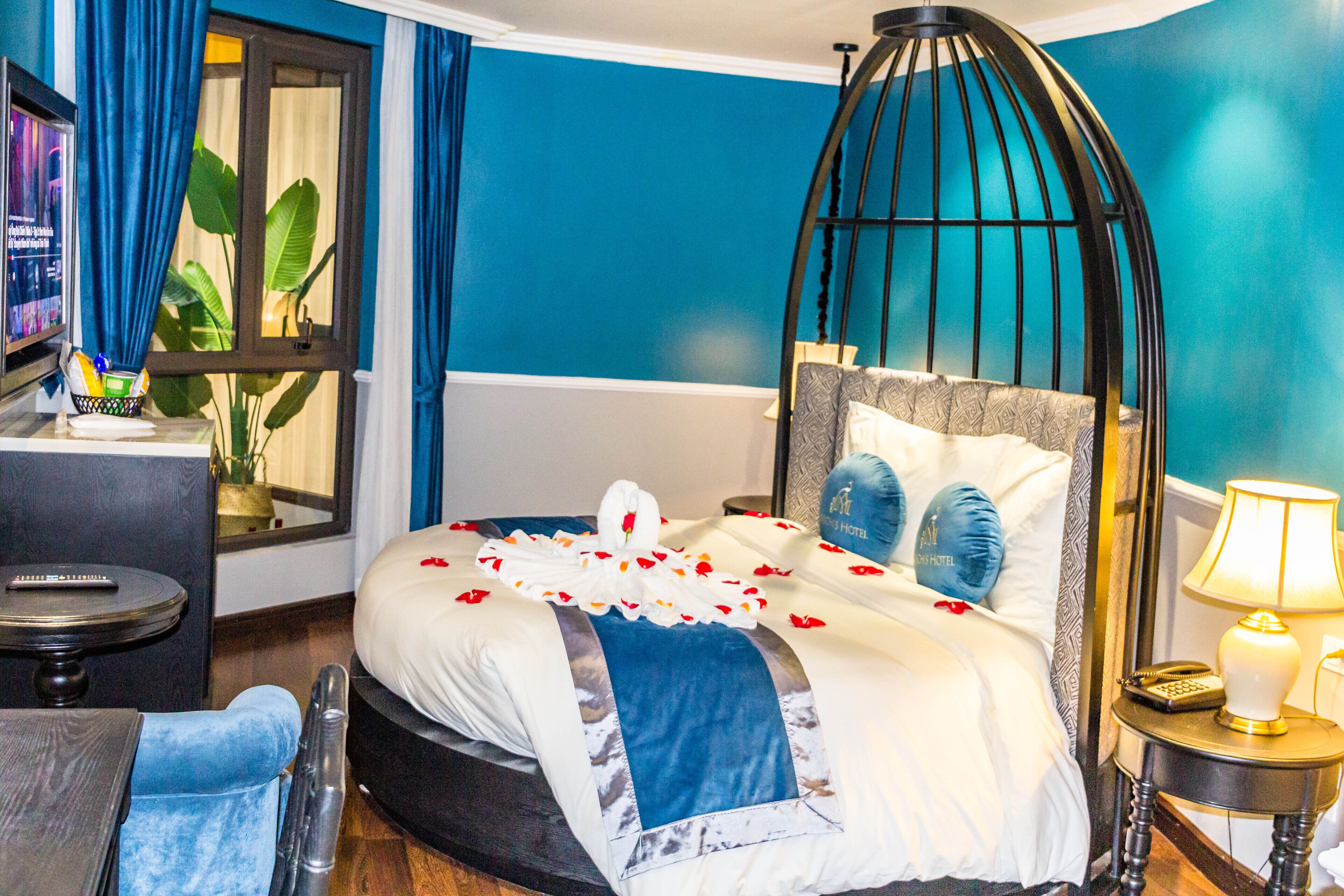 A hotel room with a bed, a bedside table with a lamp, a chair, and a TV on a stand.