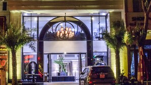 L’extérieur de l’hôtel Michi, avec son entrée imposante, un grand lustre et une voiture garée devant.