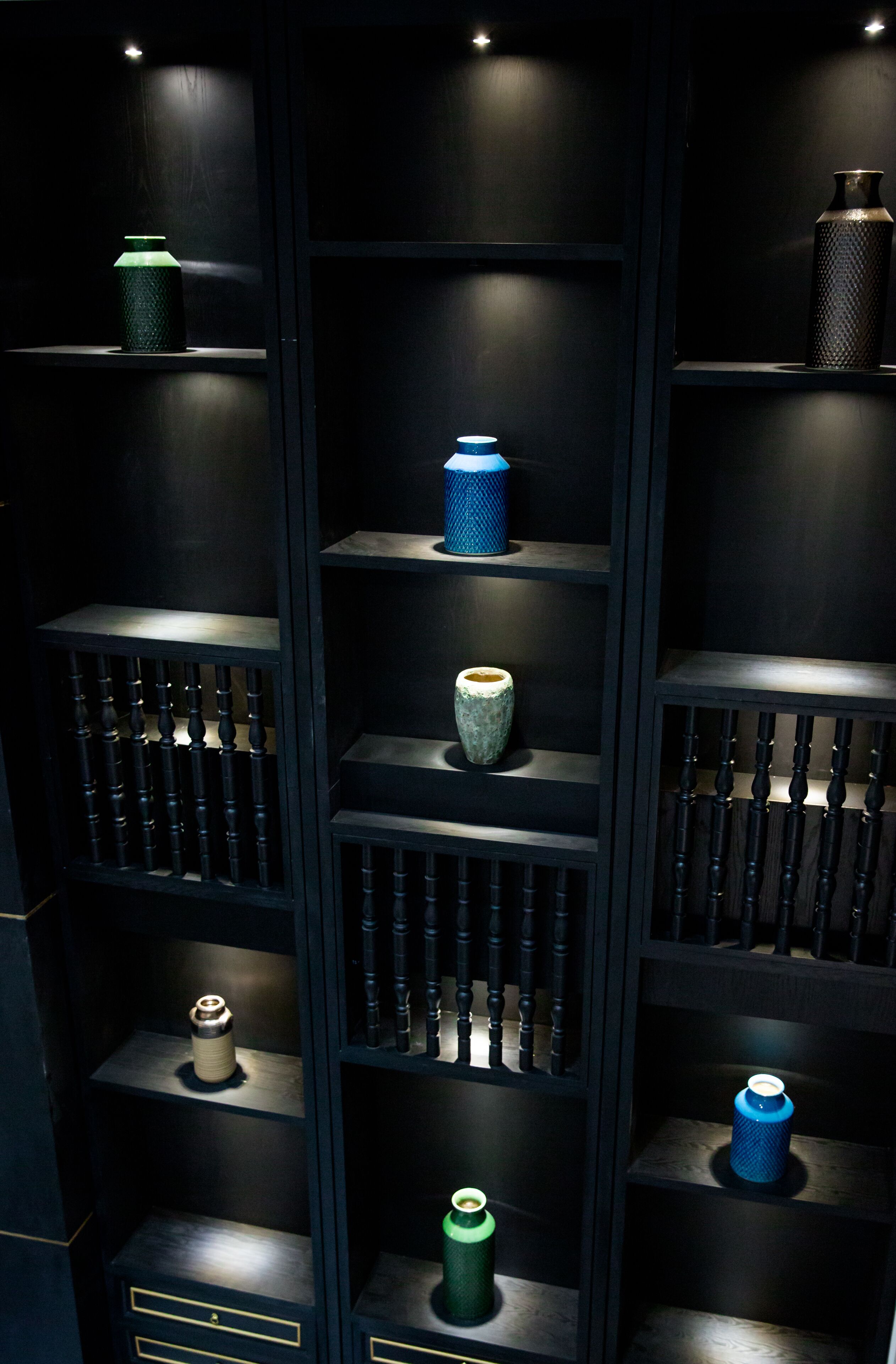 A dark wooden shelving unit with various objects displayed on multiple shelves.