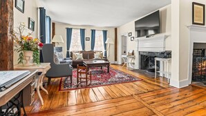 Een ruime woonkamer met een open haard, houten vloeren, een bank en een salontafel.