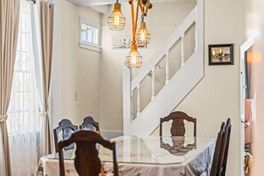 A dining area with a glass table, wooden chairs, and a staircase with a railing.