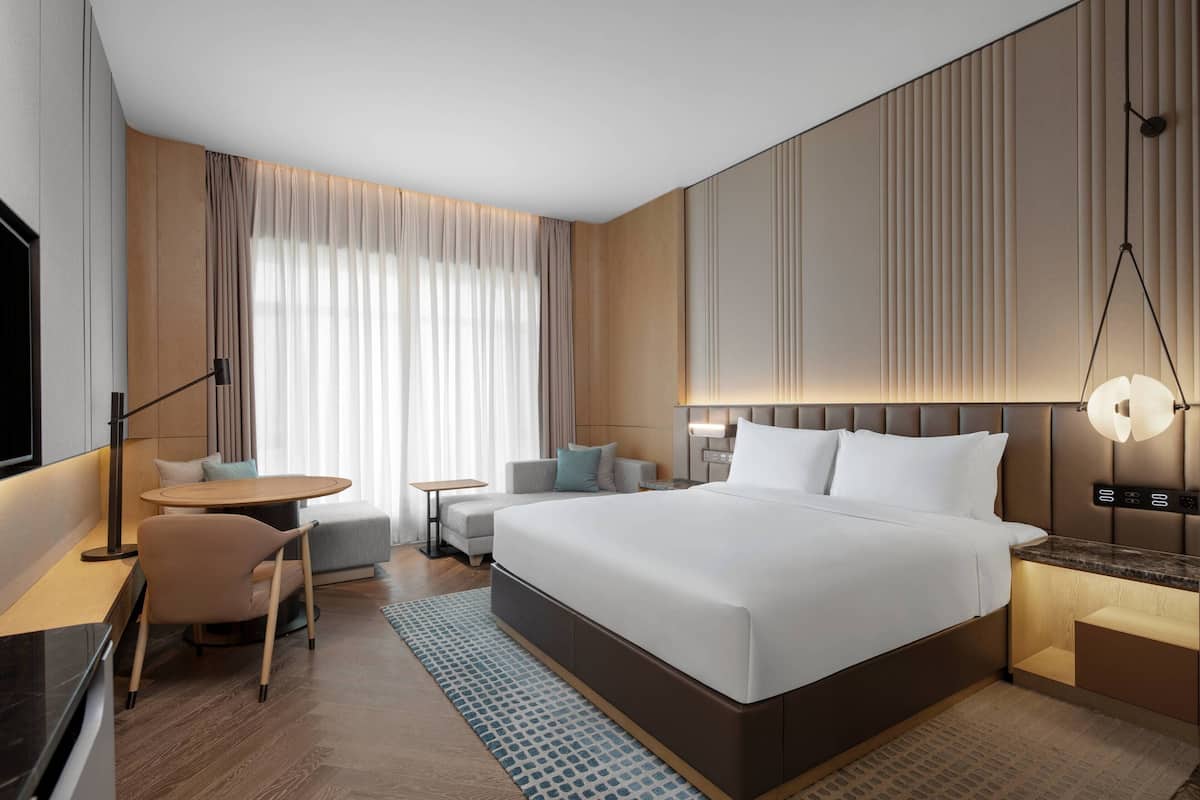 Une chambre d’hôtel moderne équipée d’un grand lit, d’un bureau, d’une chaise, d’une petite table et d’un téléviseur.