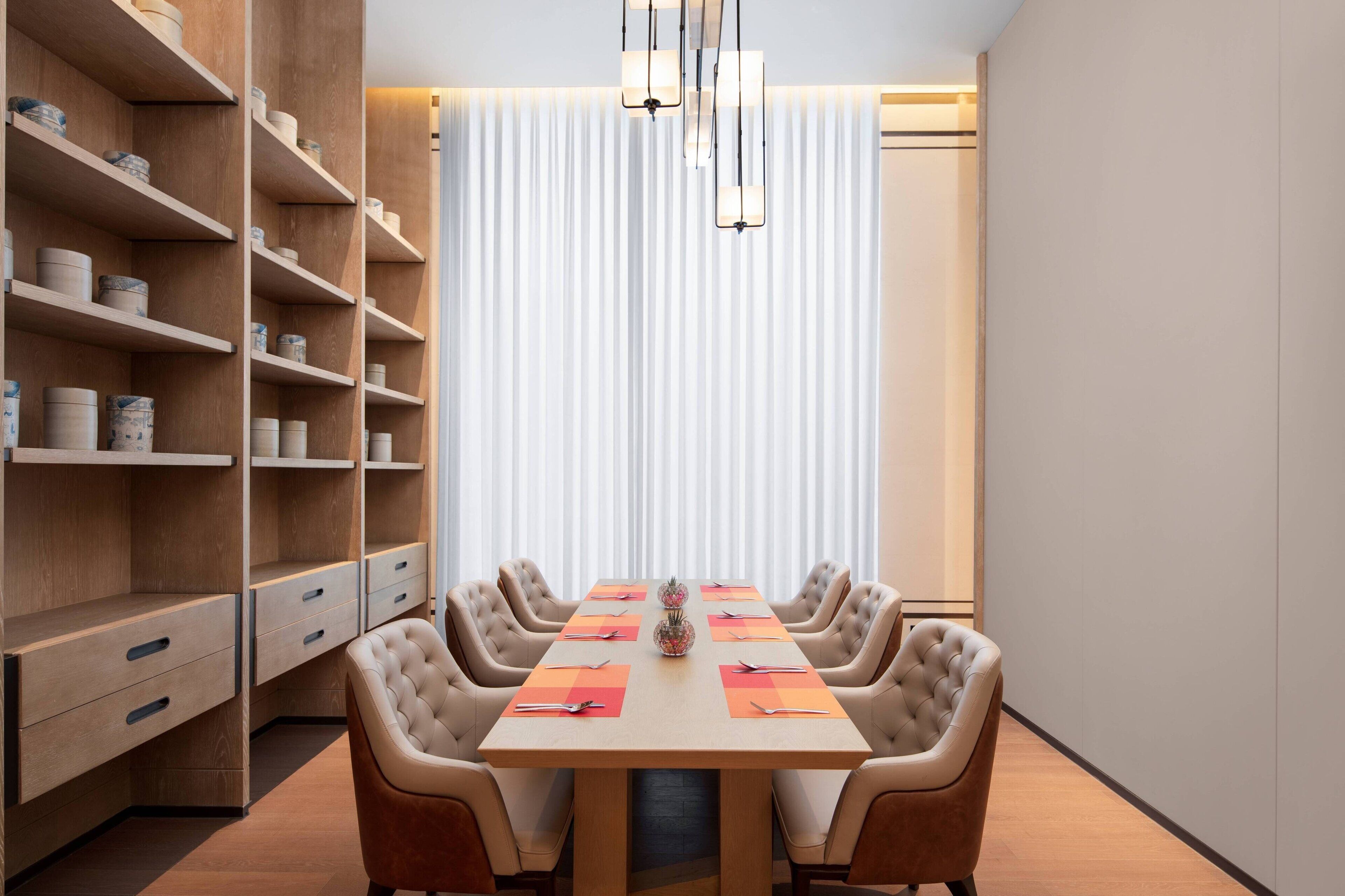 Une salle de conférence équipée d’une longue table, de six chaises et d’une bibliothèque avec des boîtes de rangement.