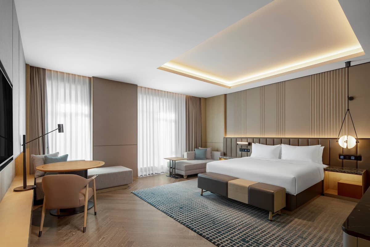 Une chambre d’hôtel moderne dotée d’un grand lit, d’un coin salon, d’un bureau et d’une télévision.
