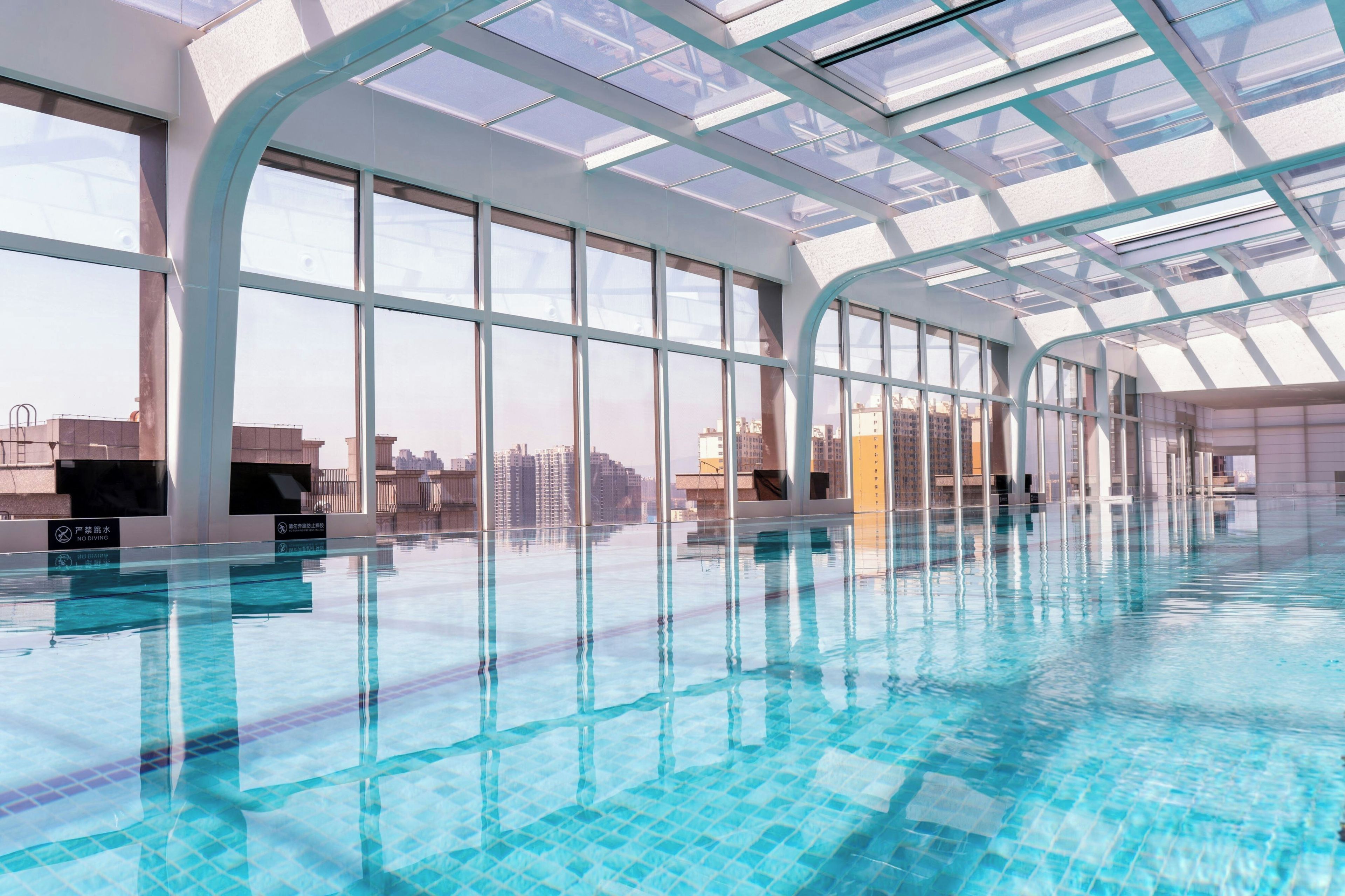 Una piscina interior con paredes de vidrio transparente y vistas a la ciudad.