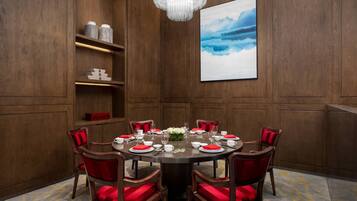 A conference room with a round table, red chairs, and a chandelier.