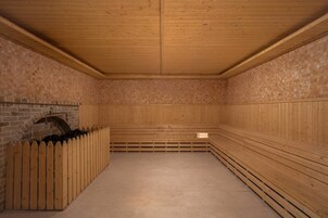 Una sauna con bancos de madera, pared de ladrillo y techo de madera.