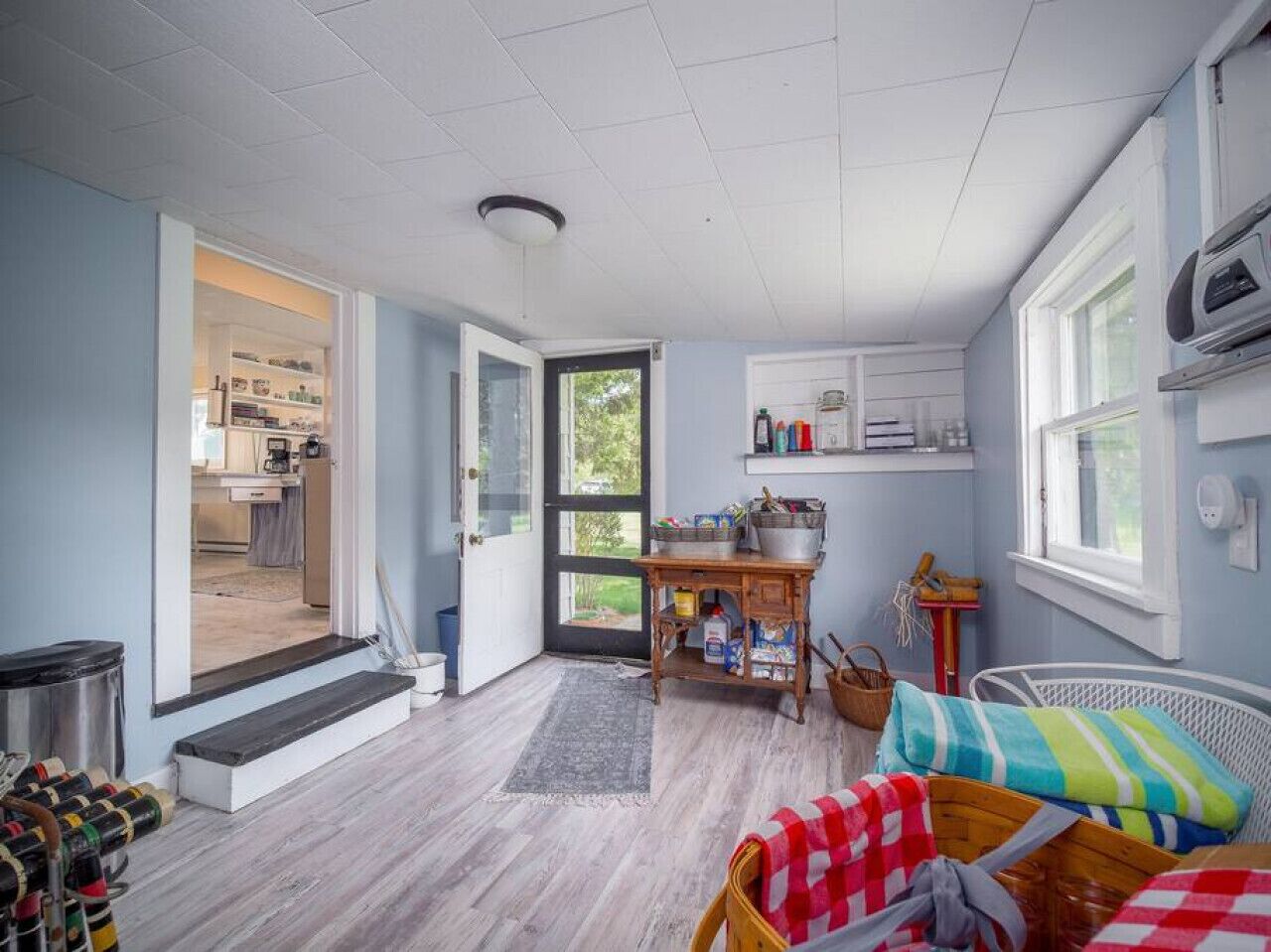 Une pièce confortable avec un lit, une petite table sur laquelle sont posés quelques objets, une fenêtre et une porte qui donne sur la cuisine.