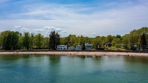 En vacker utsikt över sjön med flera hus längs stranden, en sandstrand och ett stilla vattenområde.