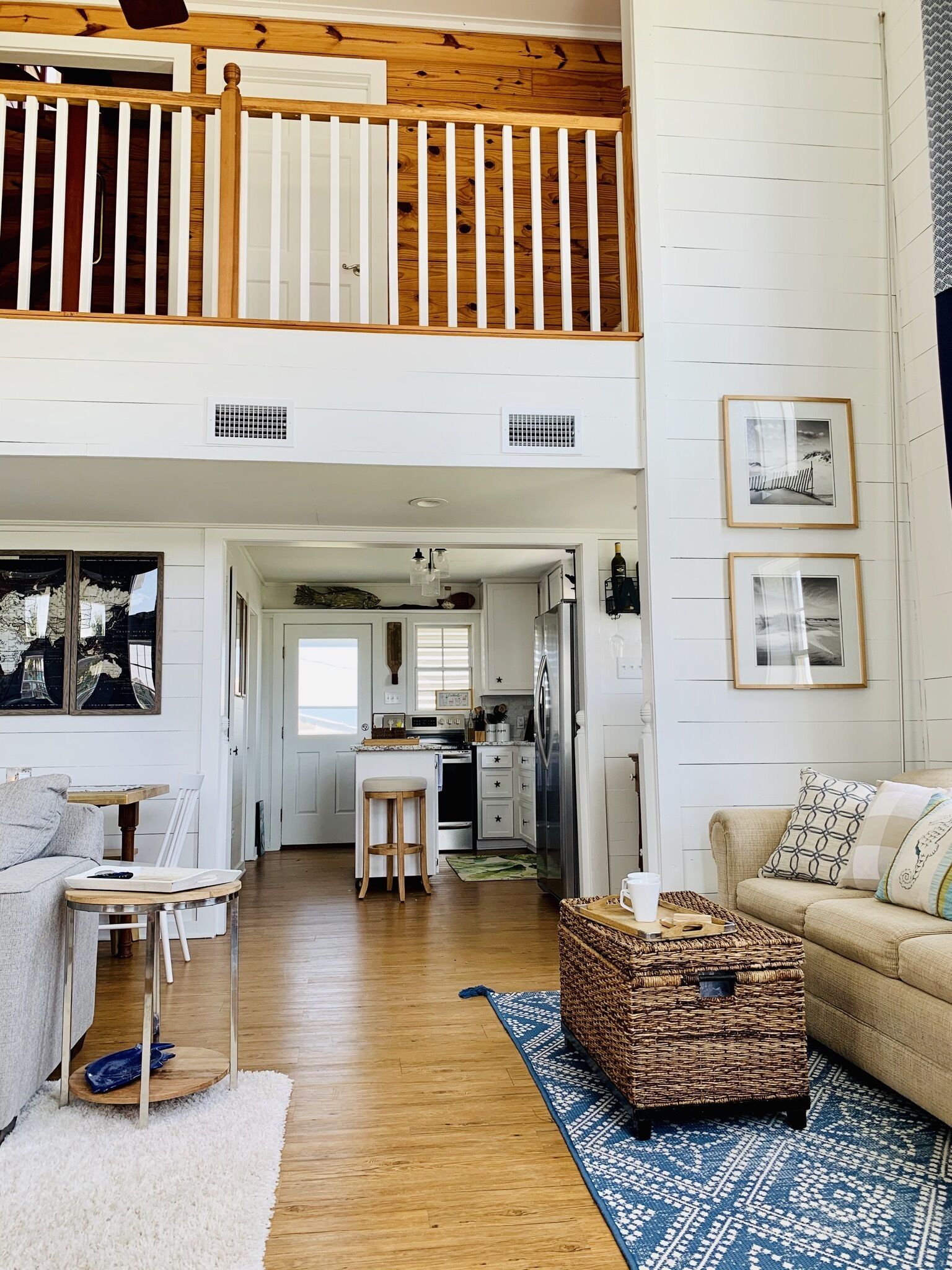 A spacious living area with a high ceiling, a wooden staircase, a kitchen, and a dining area.